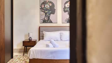 Una camera da letto con un letto, un comodino, una lampada e due opere d'arte floreali alle pareti.