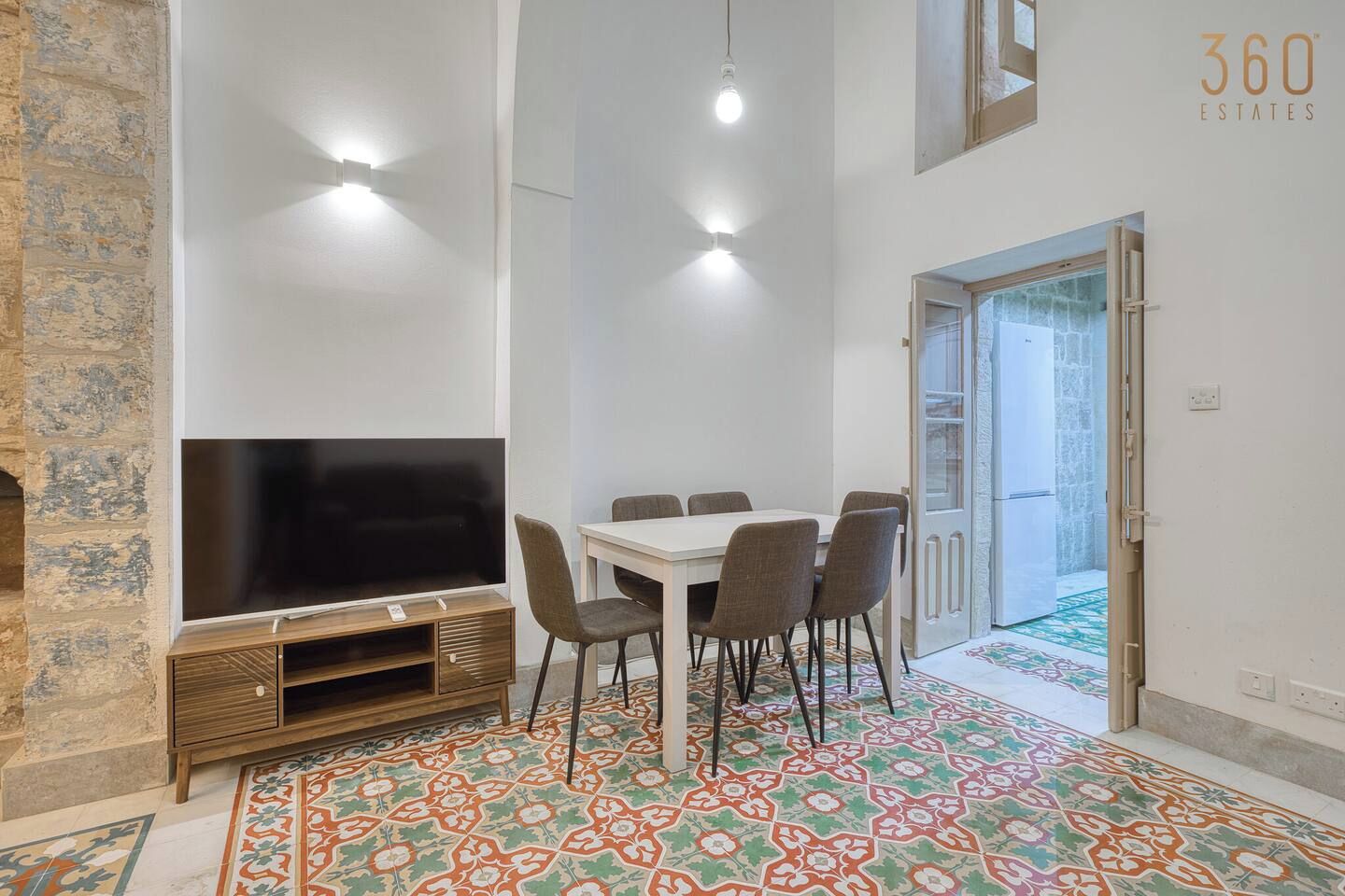 A dining area with a TV, chairs, and a patterned floor.