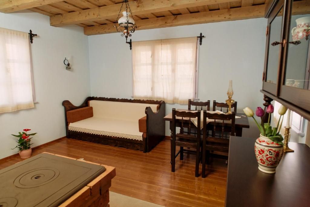 Una sala de estar acogedora con un sofá, mesa de comedor, sillas y una mesita con un jarrón de flores.