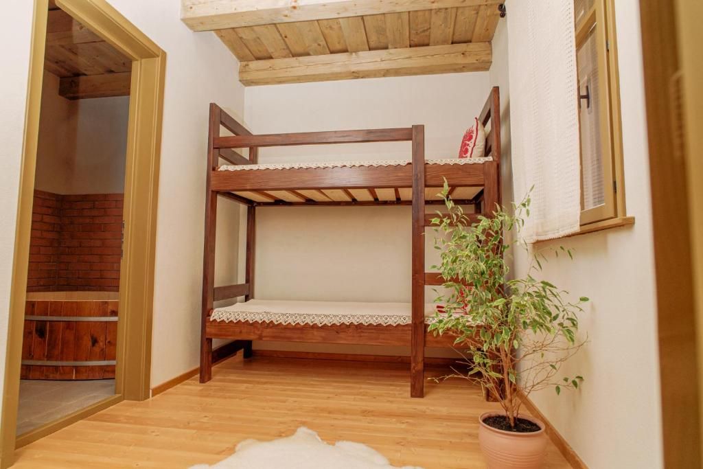 A bunk bed with a lace-trimmed mattress, a potted plant, and a wooden bench.