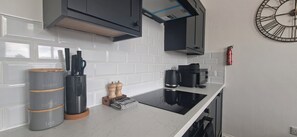 A modern kitchen with white subway tiles, a coffee machine, a kettle, and a clock on the wall. - Deluxe one-bed apartment in Yaxley near A1 (Yaxley)