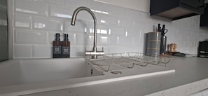 A kitchen with a stainless steel faucet, a dish soap dispenser, a hand soap dispenser, and a spice rack. - Deluxe one-bed apartment in Yaxley near A1 (Yaxley)