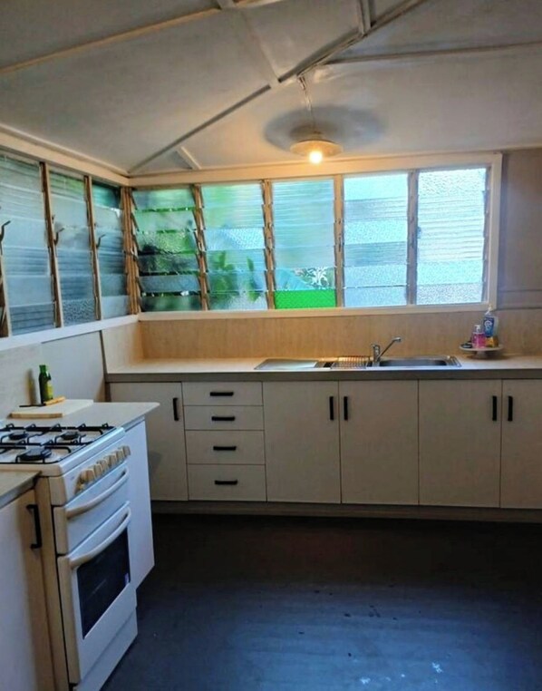 A kitchen with a gas stove, a sink, and cabinets.