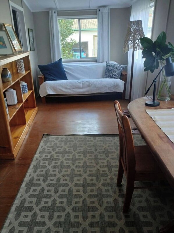 A bedroom with a bed, a bedside table, a lamp, a chair, and a window with curtains.