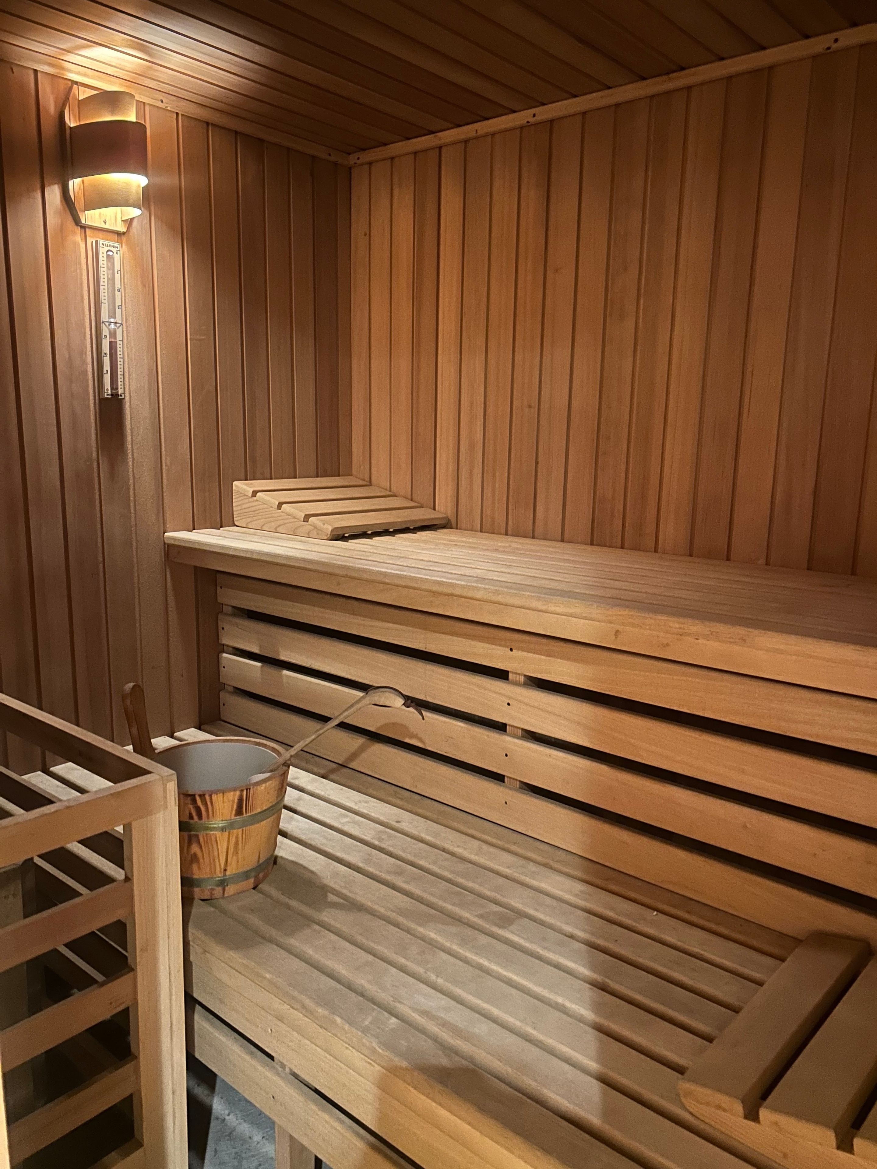 A sauna with wooden benches and a wall-mounted light fixture.