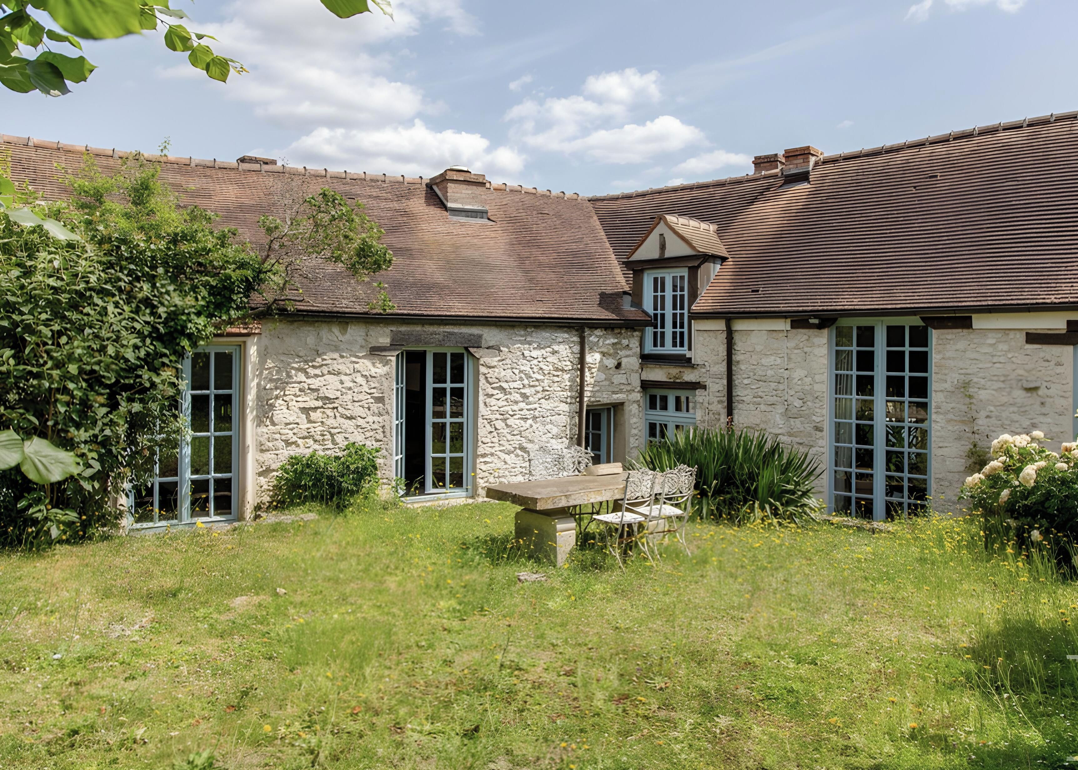 A stone building with multiple windows and a grassy yard.