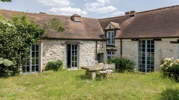 A stone building with multiple windows and a grassy yard.