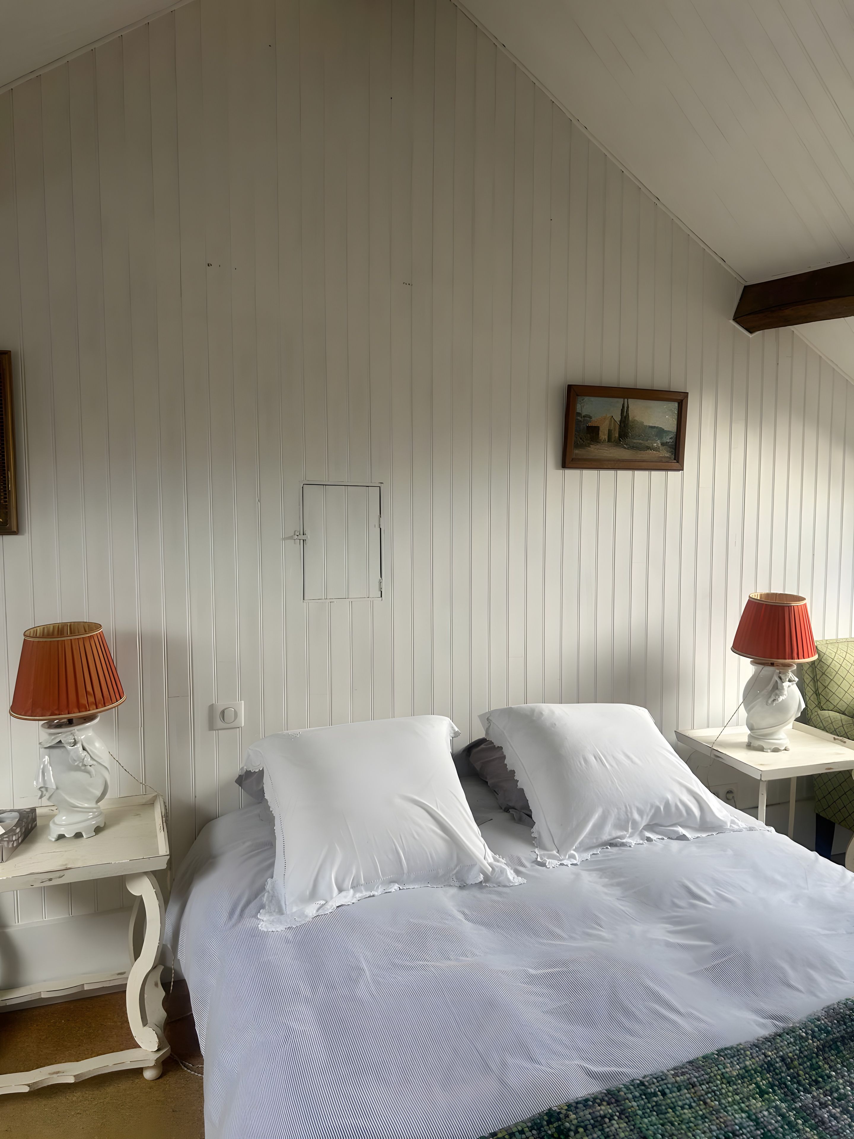 Un dormitorio con una cama, dos mesitas de noche, una lámpara, un cuadro y una ventana.