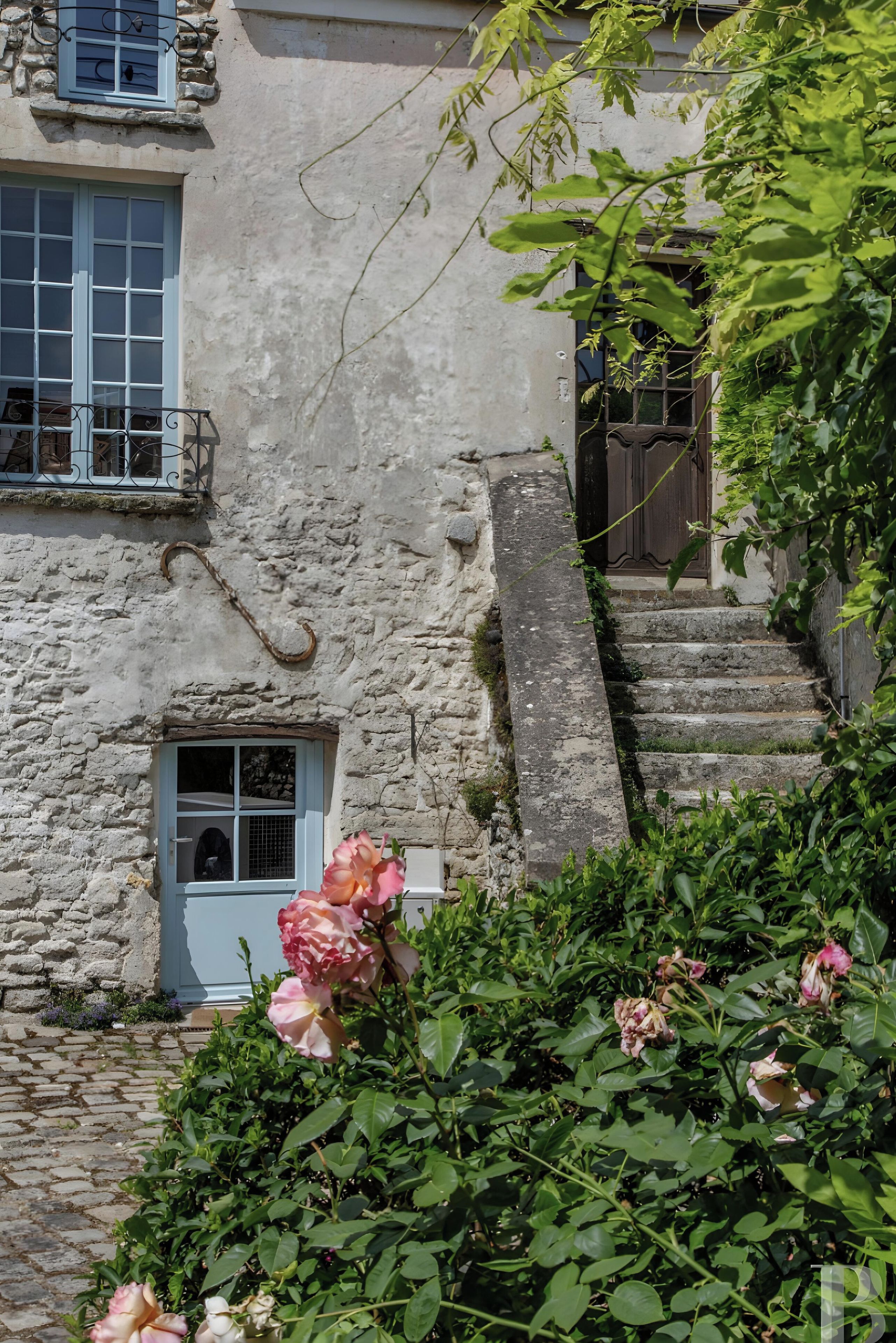 Un bâtiment en pierre doté d’une petite fenêtre, d’une porte et d’un escalier en pierre menant à une porte en bois.