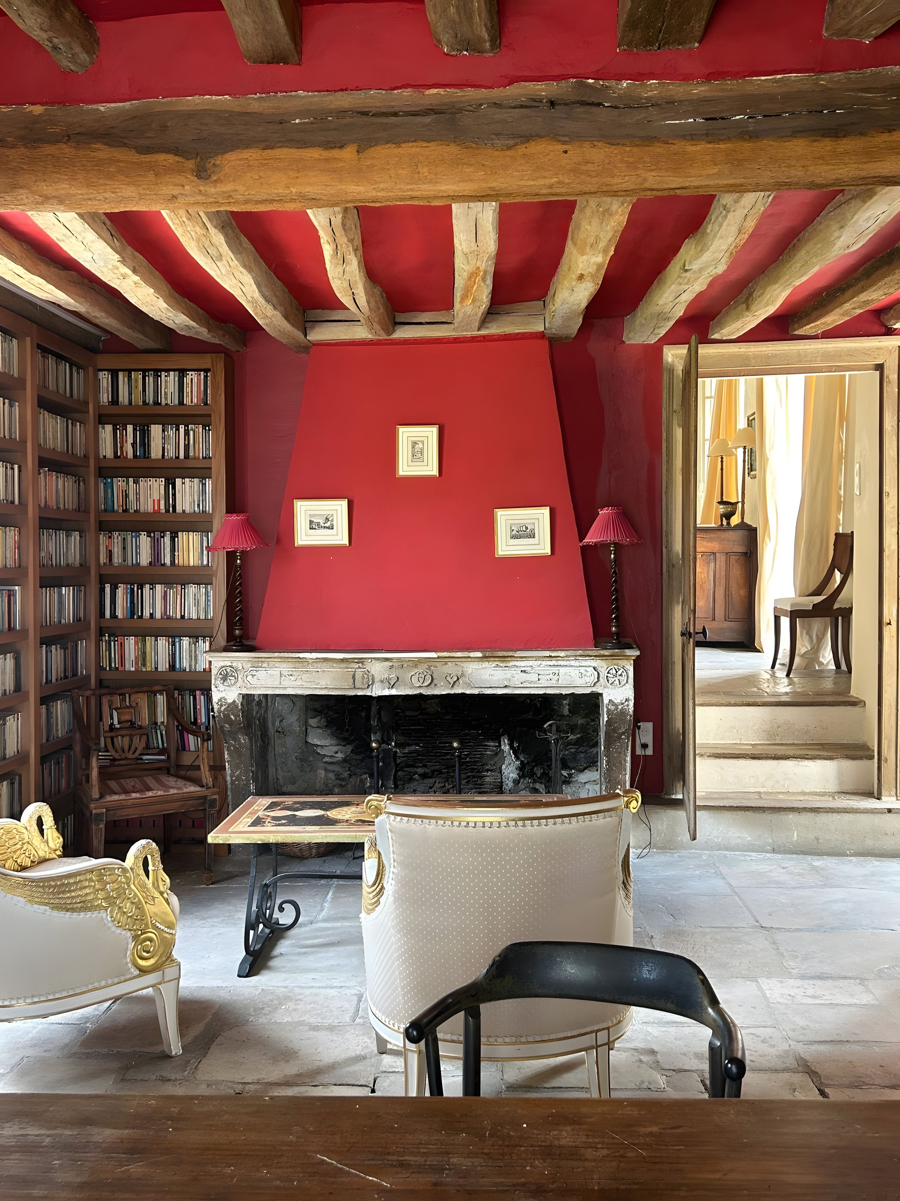 Een kamer met een open haard, boekenplanken, een eettafel en een stoel.