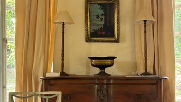 Una habitación con un aparador de madera, dos lámparas, un cuadro enmarco y una silla.