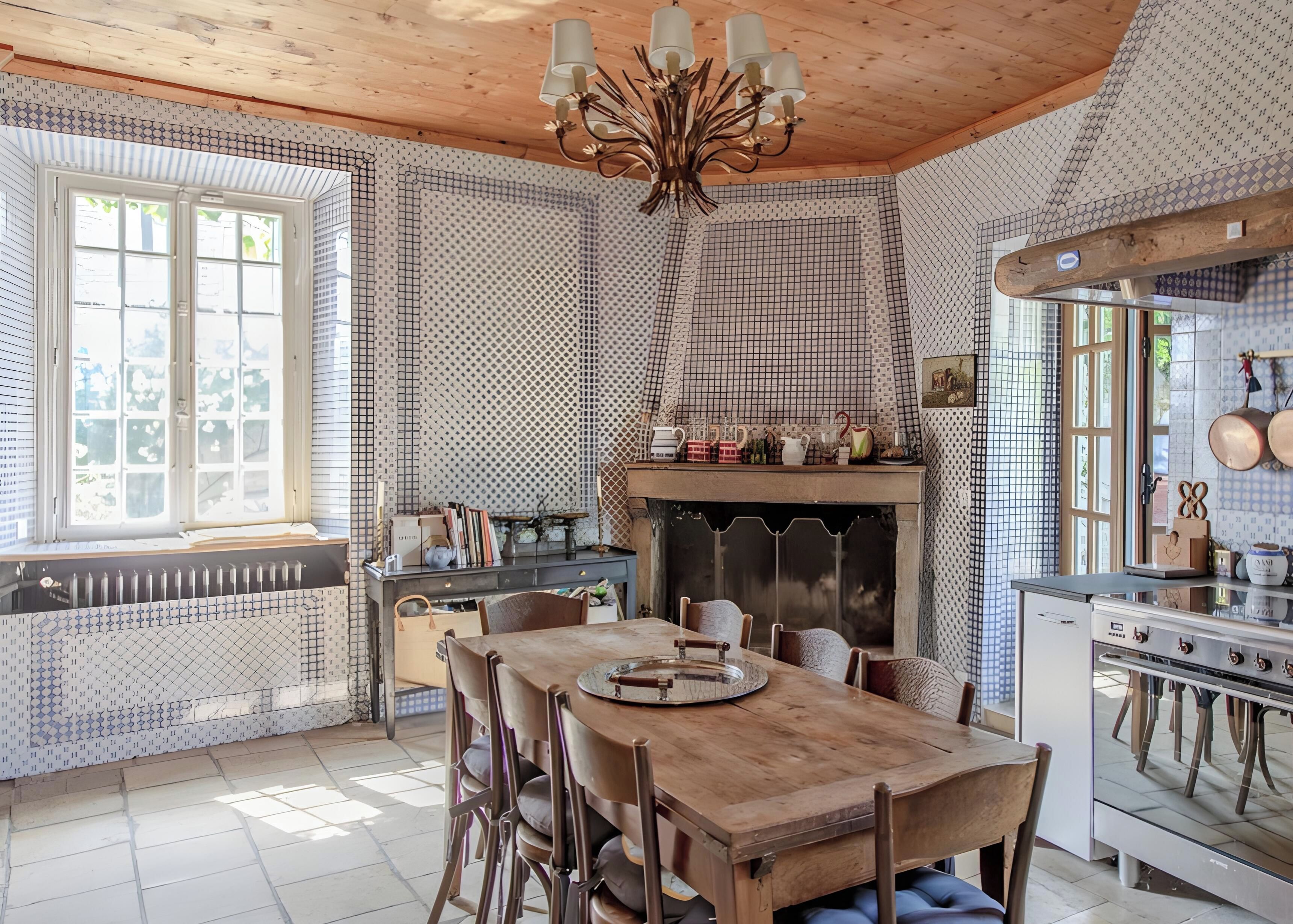 Una cucina con un tavolo di legno, sedie, un piano cottura e una parete decorata.