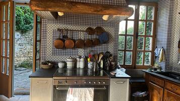 A kitchen with a stove, oven, and hanging pots.