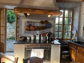 Una cocina con estufa, horno y ollas colgantes.