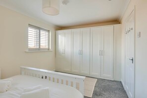 A bedroom with a bed, a window with blinds, a wardrobe, and a radiator. - Spacious 4-Bed Marina Home, Parking, Near City (Liverpool)