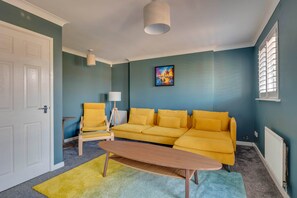 A room with a yellow sofa, a wooden coffee table, a lamp, and a painting on the wall. - Spacious 4-Bed Marina Home, Parking, Near City (Liverpool)