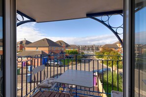 A balcony with a table and chairs, overlooking a residential area with houses and parked cars. - Spacious 4-Bed Marina Home, Parking, Near City (Liverpool)