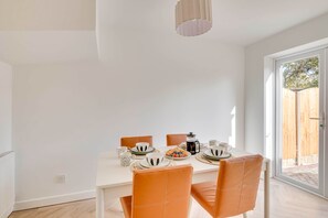 A dining area with a white table, orange chairs, and a coffee pot. - Spacious 4-Bed Marina Home, Parking, Near City (Liverpool)