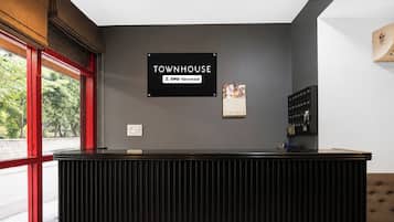 A reception desk with a sign that reads 'TOWNHOUSE OYO-Serviced' and a calendar with the brand 'BHIMA' on the wall.