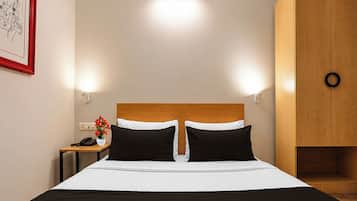 A hotel room with a bed, bedside tables, a nightstand, a lamp, a framed picture, and a wardrobe.
