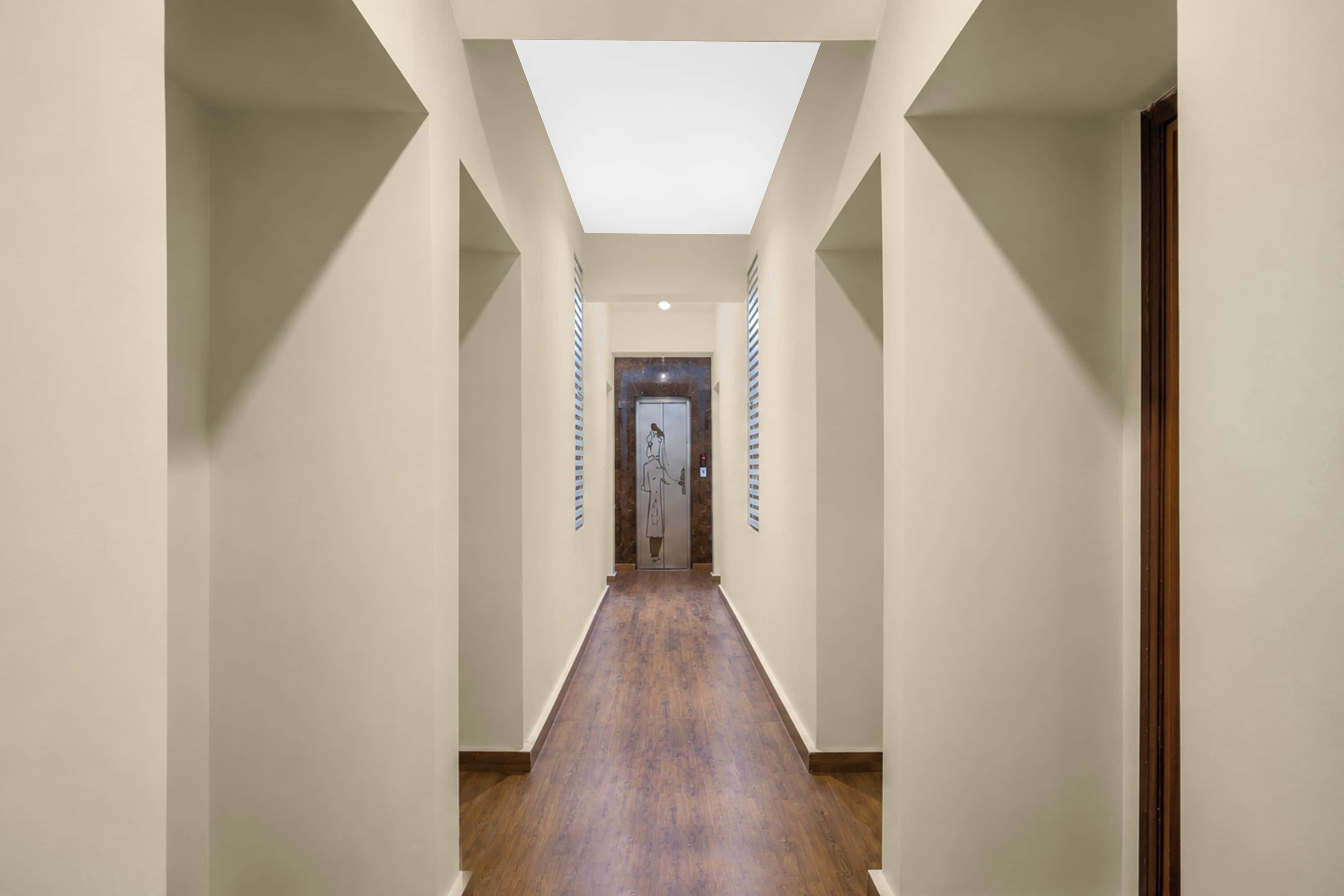 A hallway with a skylight, wooden flooring, and a door at the end.