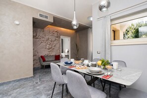 Un espace repas moderne avec une table en marbre, des chaises à revêtement gris et un élément décoratif mural.