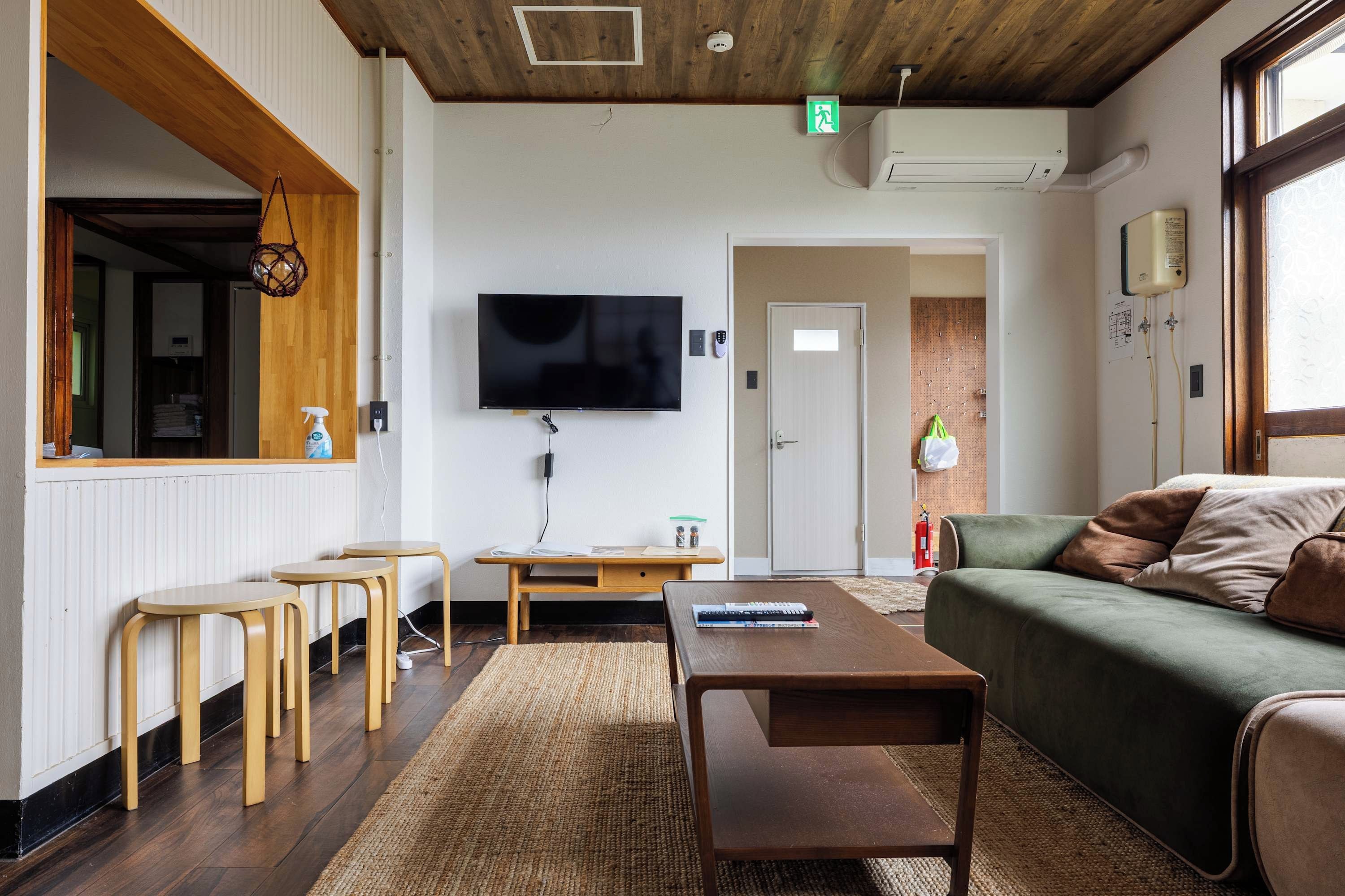 Un salon moderne avec un téléviseur à écran plat, des meubles en bois, un canapé vert et une cheminée.