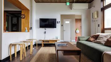 Un salon moderne avec un téléviseur à écran plat, des meubles en bois, un canapé vert et une cheminée.
