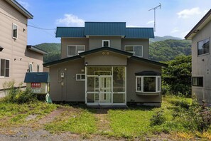 A two-story residential building with a front entrance, a small porch, and a visible satellite dish.
