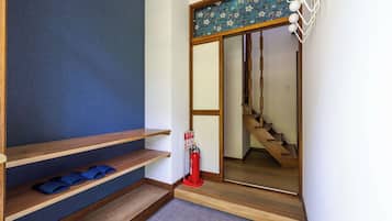 Un couloir avec des marches en bois, un extincteur et un mur bleu.