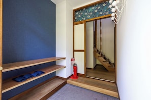 Een hal met houten traptreden, een brandblusser en een blauwe muur.