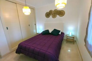 Ein Schlafzimmer mit einem Bett, zwei Nachttischen, einem Kleiderschrank und einer Wandleuchte.
