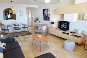 Una sala de estar moderna con comedor, televisor y sofá.