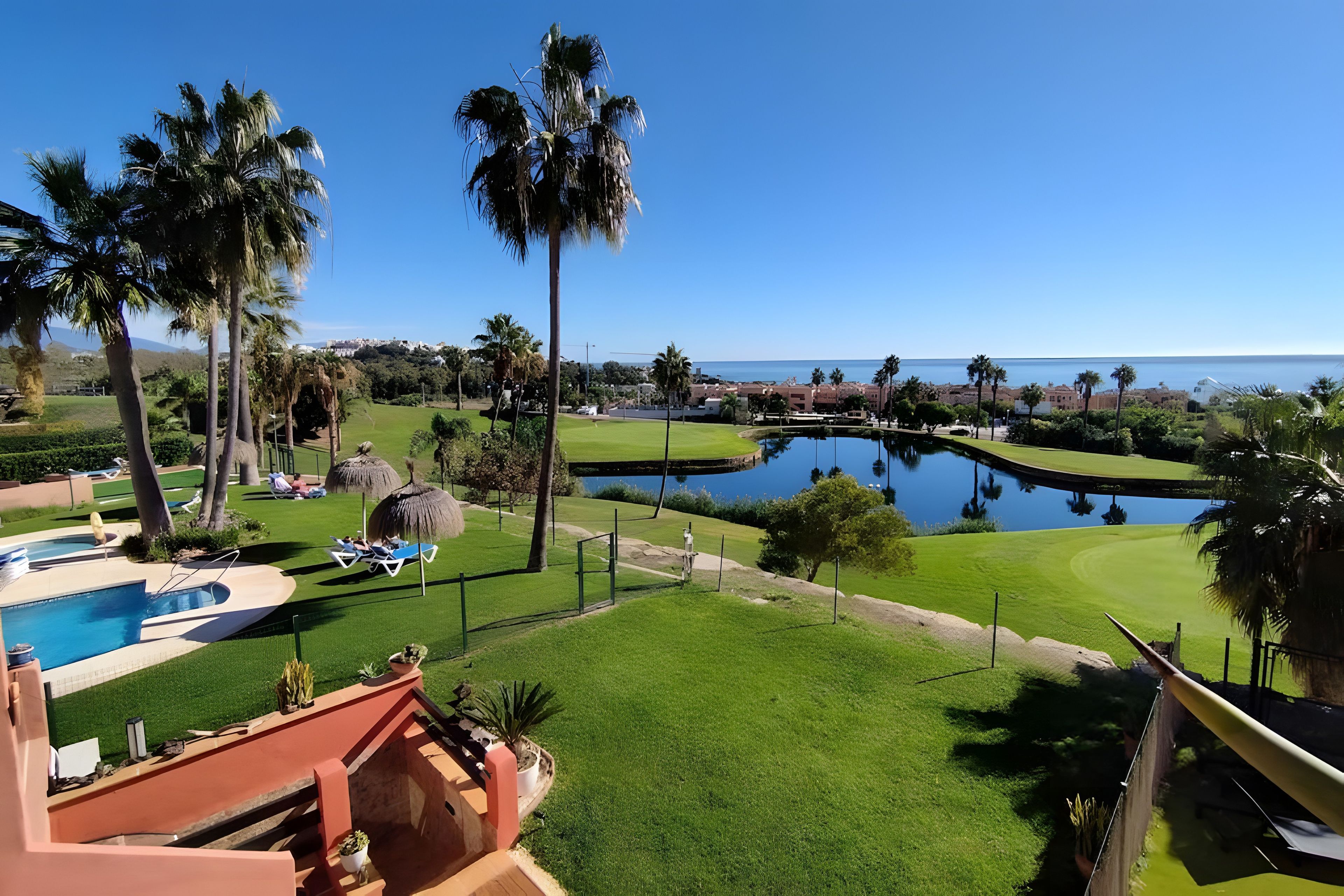 Un parcours de golf doté d’une piscine, de palmiers et offrant une vue sur l’océan.