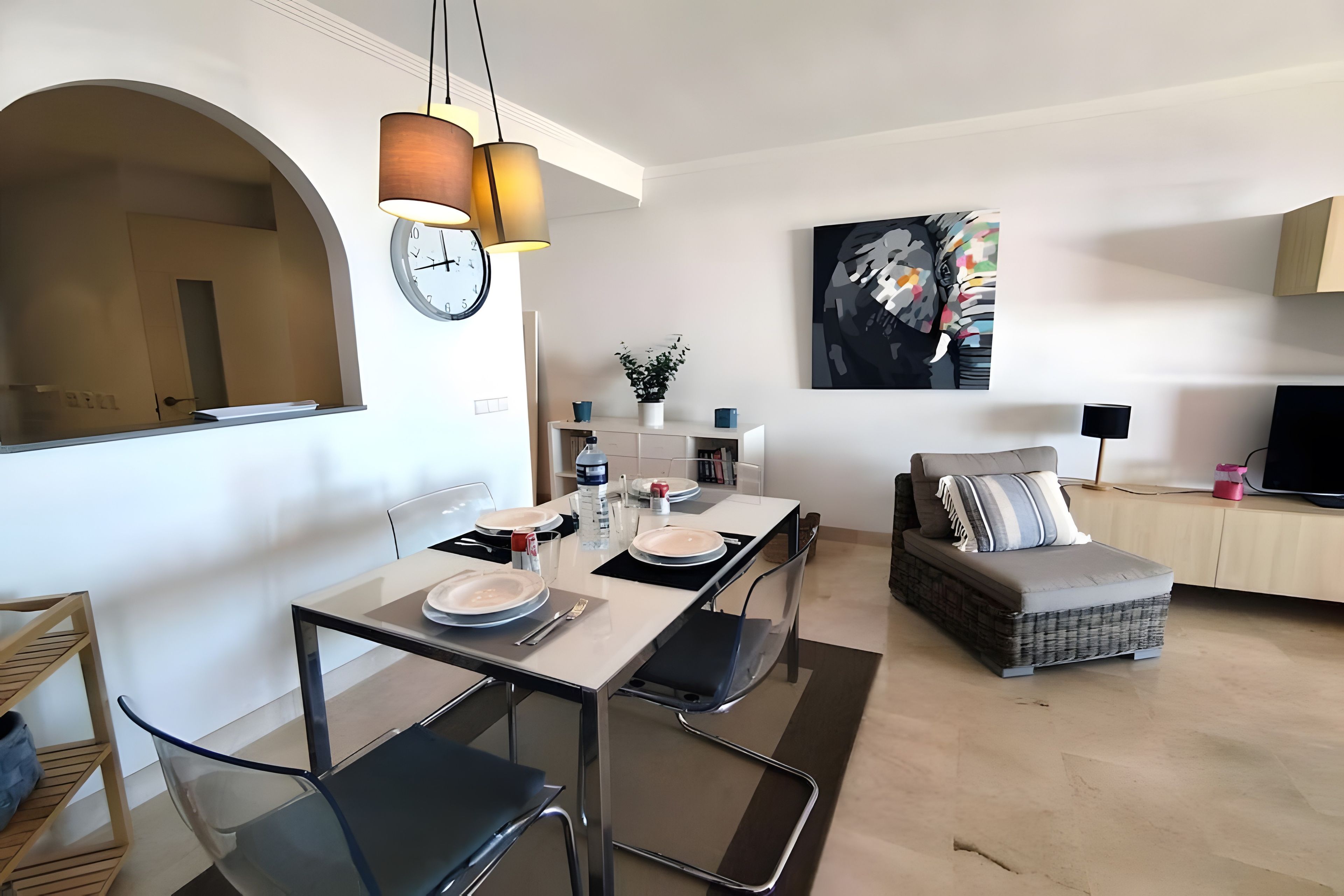Un espacio habitable moderno con comedor, sofá, televisor y un cuadro en la pared.