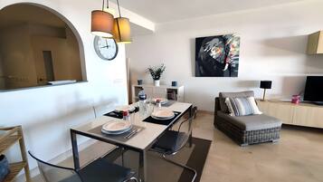 Un espacio habitable moderno con comedor, sofá, televisor y un cuadro en la pared.