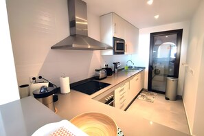 Una cocina moderna con una campana extractora de acero inoxidable, microondas y horno empotrado.