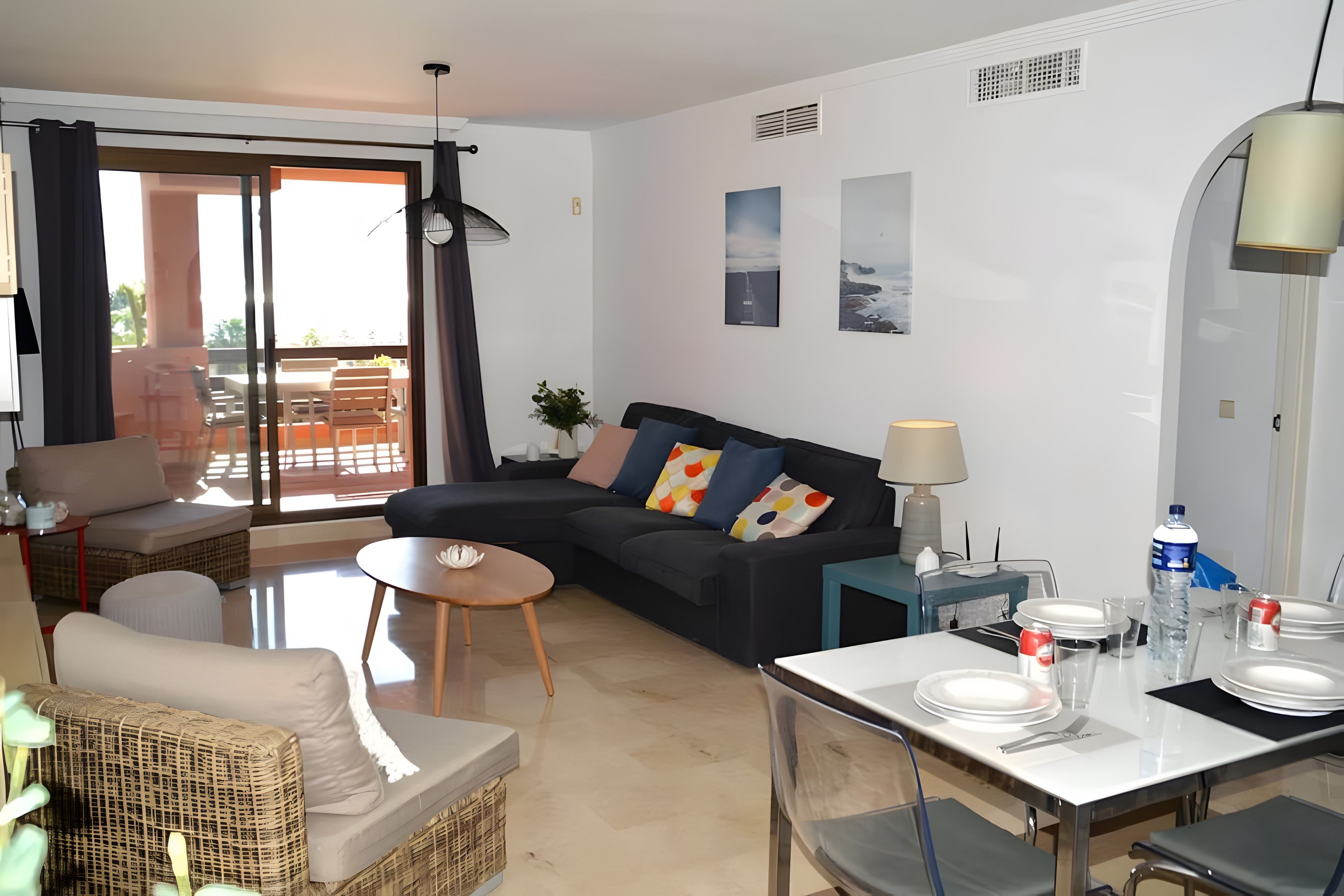 Ein modernes Wohnzimmer mit einer Couch, einem Esstisch für zwei Personen und einem Balkon mit Blick.