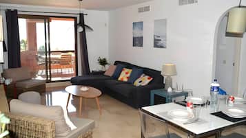 Ein modernes Wohnzimmer mit einer Couch, einem Esstisch für zwei Personen und einem Balkon mit Blick.