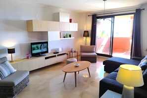 Una sala de estar moderna con un televisor de pantalla plana, un sofá, un sillón y una mesita.