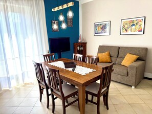 A dining area with a wooden table, chairs, a television, and artwork on the wall. - Cozy apartment with an outdoor terrace in the heart of the Val di Chiana (Sinalunga)