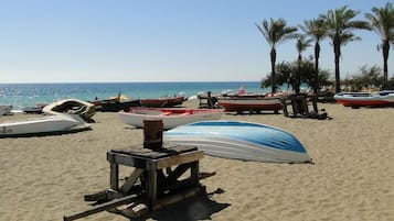 A beach with several boats and a wooden structure, likely a lifeguard stand, under a clear sky.