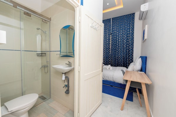 Un bagno con cabina doccia in vetro, lavandino e WC.
