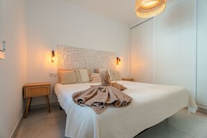 Ett sovrum med en stor säng, dekorativa väggpaneler, sänglampor och en hängande taklampa.