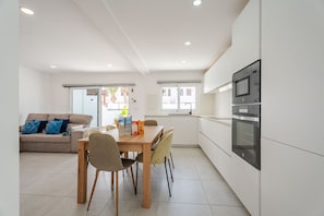 A modern kitchen with a built-in oven and a dining area with a table and chairs. - Casa Marlena- Private Terrace- 4 min to the beach by Lanzarote Vacation Homes (Puerto del Carmen)