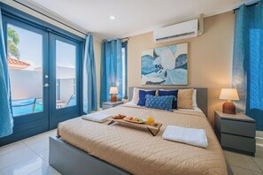 A hotel room with a bed, bedside tables, a painting, and a view of the outside. - Spacious 5BR Aruba Retreat with 2 Private Pools, Guest Apartment, 2 BBQ's & Outdoor Lounge (Noord)