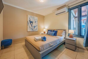 A bedroom with a bed, bedside tables, a lamp, a window, and an air conditioning unit. - Spacious 5BR Aruba Retreat with 2 Private Pools, Guest Apartment, 2 BBQ's & Outdoor Lounge (Noord)