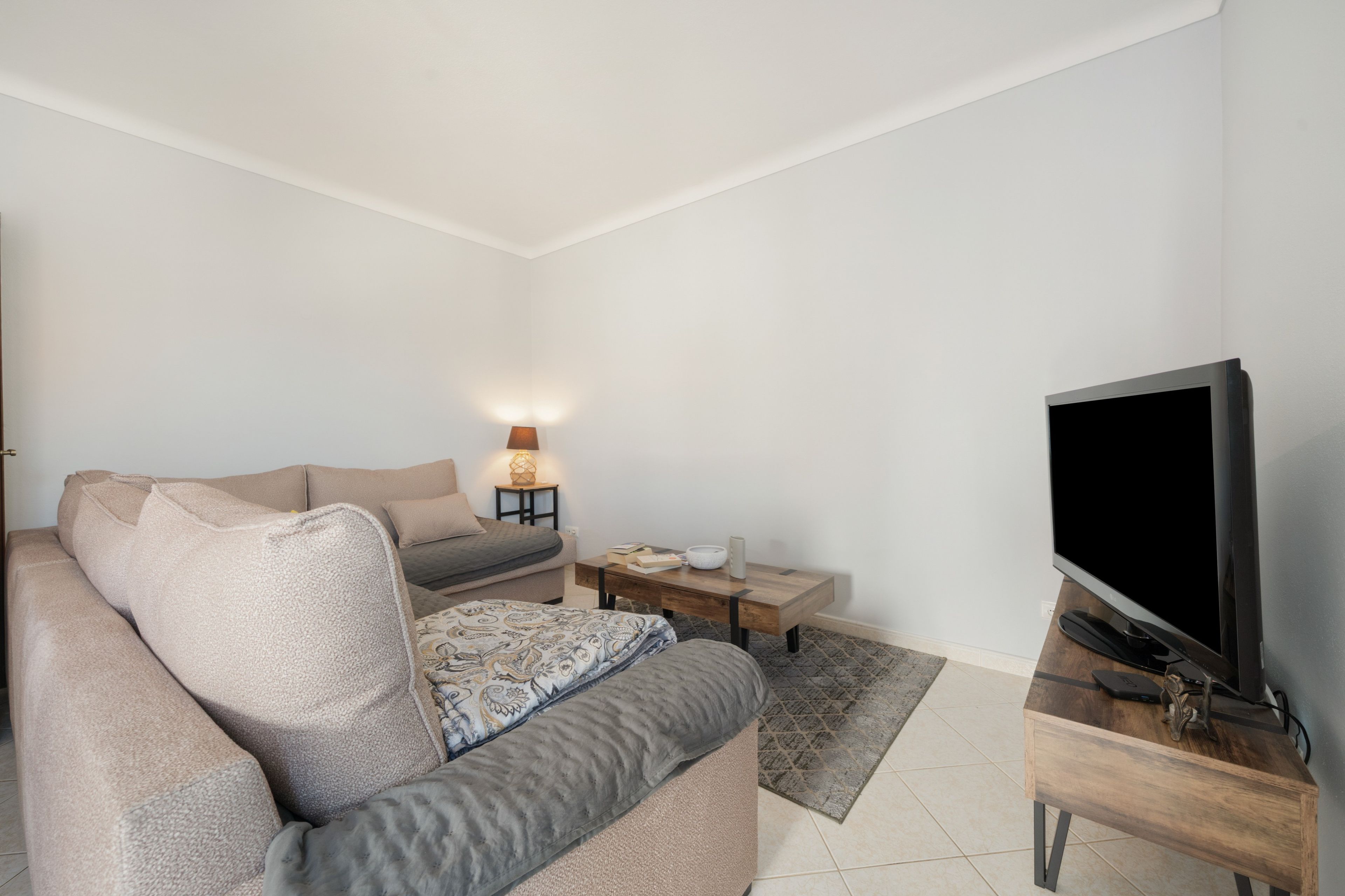 A modern living room with a sofa, a coffee table, a TV, and a lamp.