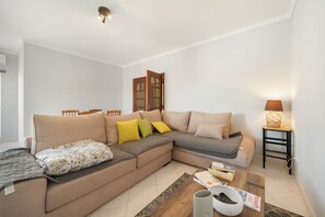 A living room with a sectional sofa, a coffee table, a lamp, and a bookshelf.