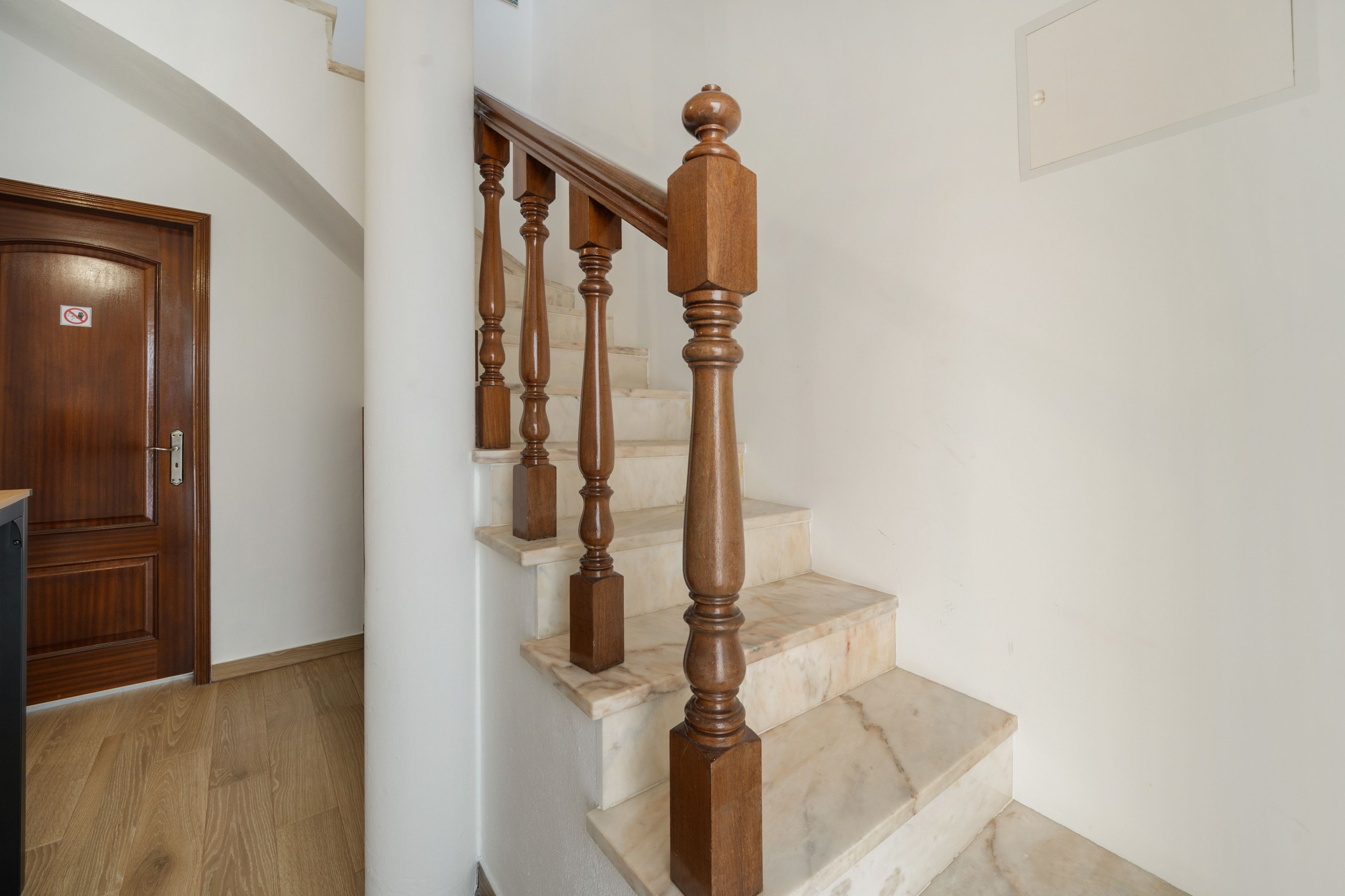 A wooden staircase with marble steps and a handrail.